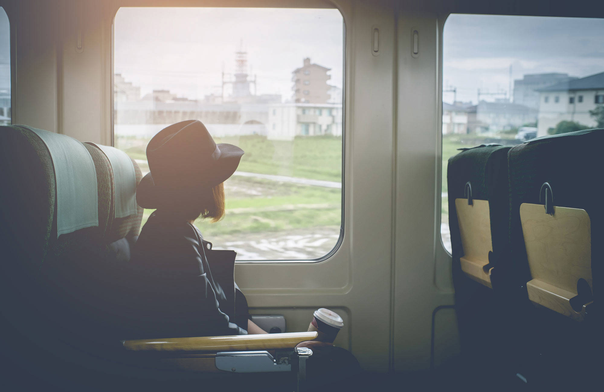 meisje met hoed kijkt uit het raam van de treincoupé | Interrailen met KILROY