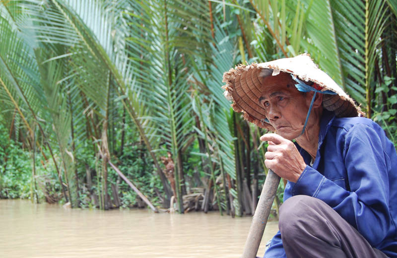 Vietnamese man roeit door de Mekong rivier in Vietnam