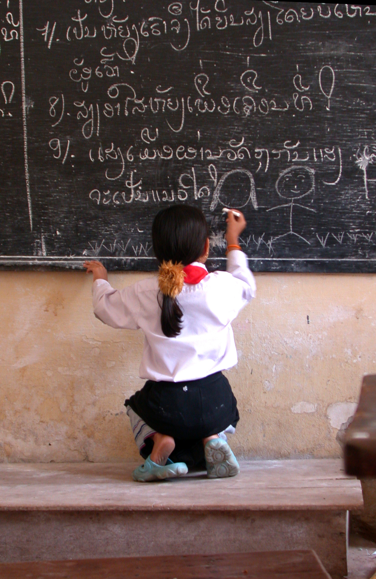 Schoolmeisje in Laos die op bord schrijft
