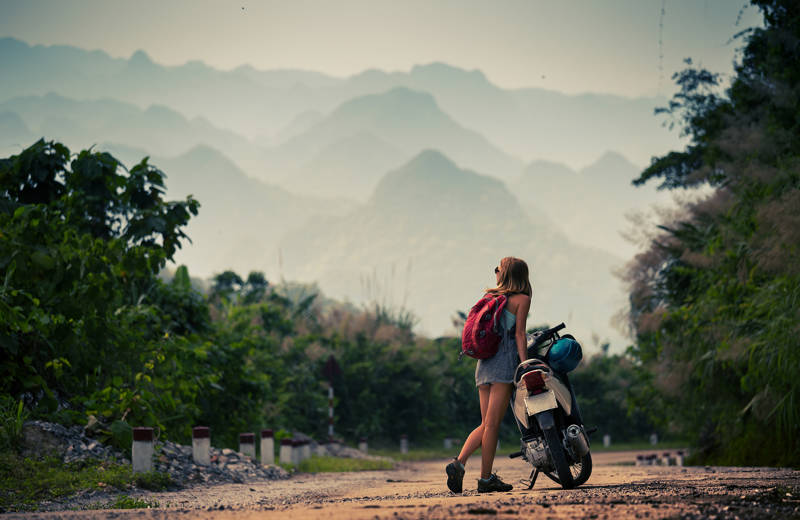 Woman with a scooter in Asia with hills in the background