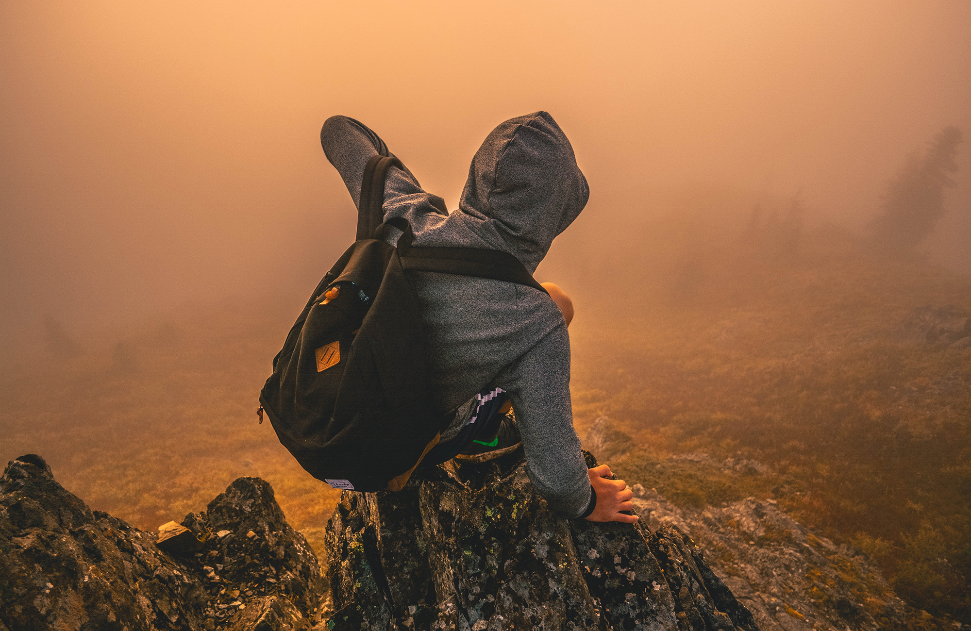 Backpacker op een steen tijdens de zonsondergang