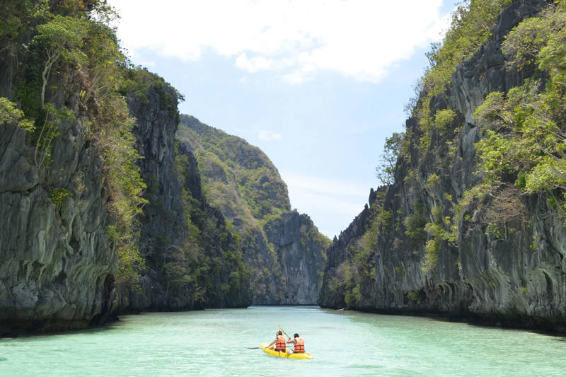 Twee mensen aan het kajakken in blauw water in El Nido, De Filipijnen
