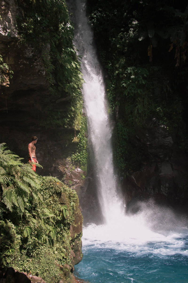 Man met rode zwembroek aan een waterval in Hinatuan, op Mindanao, Filipijnen