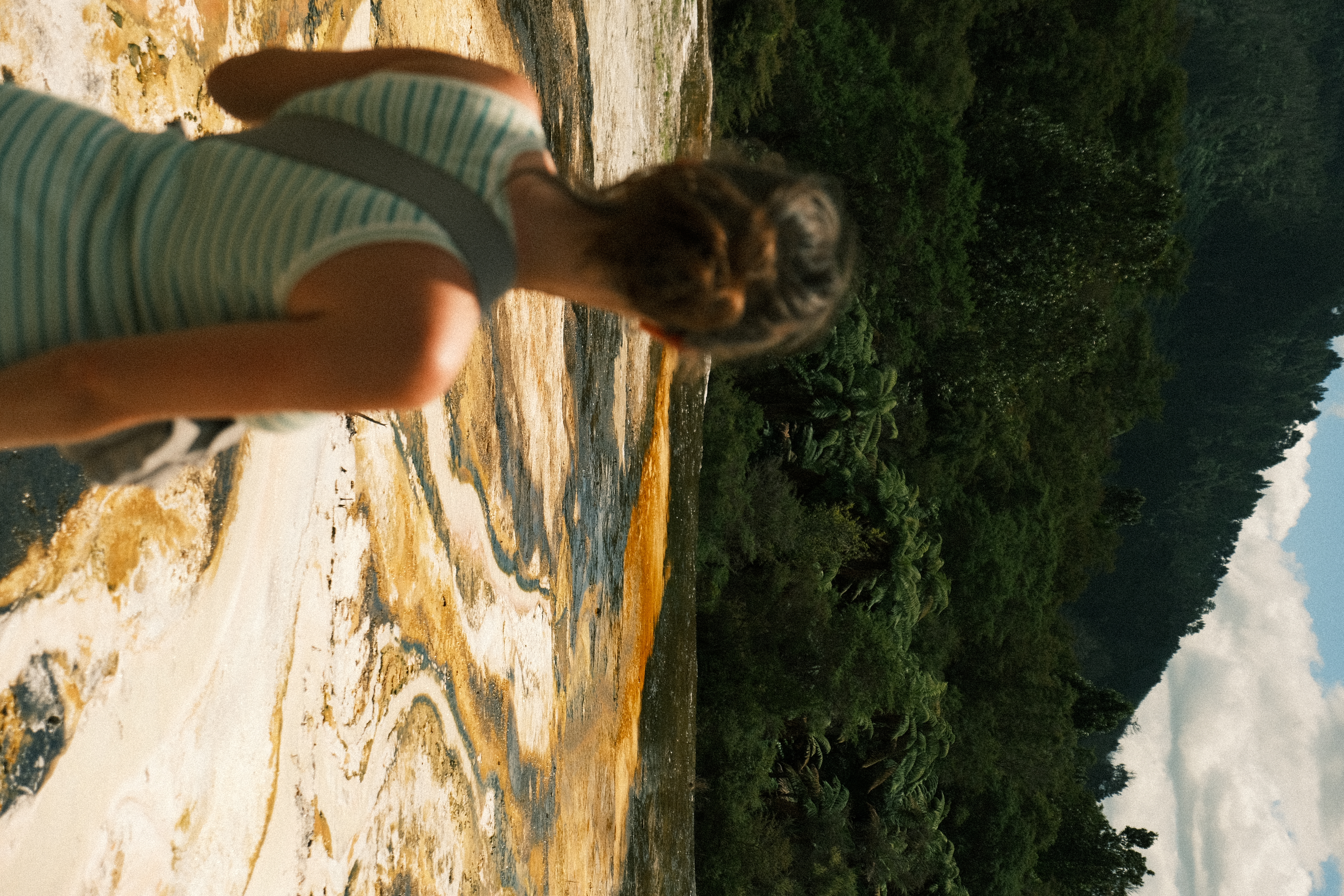 Reiziger kijkt uit over de kleurrijke geothermische bronnen en opstijgende stoom in Rotorua, Nieuw-Zeeland.