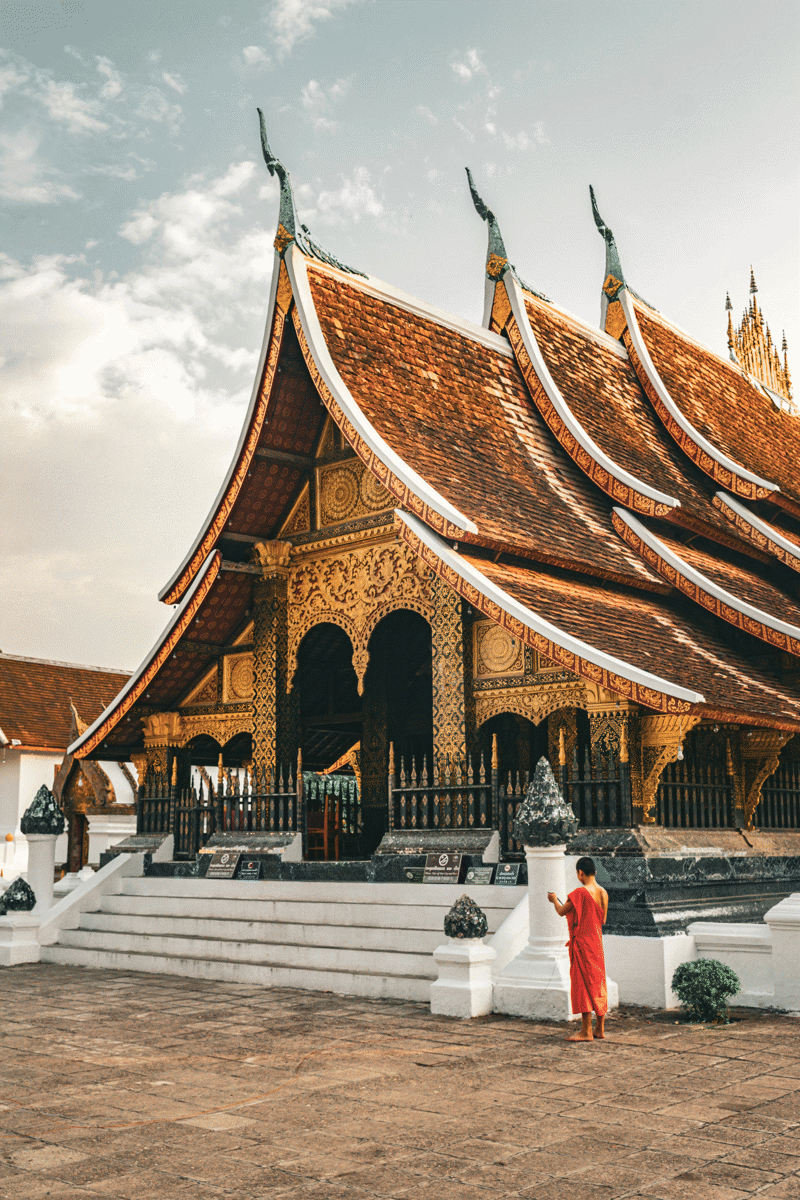 Monnik staat voor een tempel in Luang Prabang in Laos