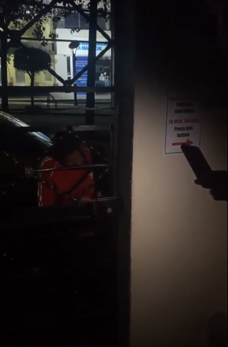 Thea zit vast achter een elektrische poort in een hotel in Quito. De taxichauffeur probeert de poort te openen.