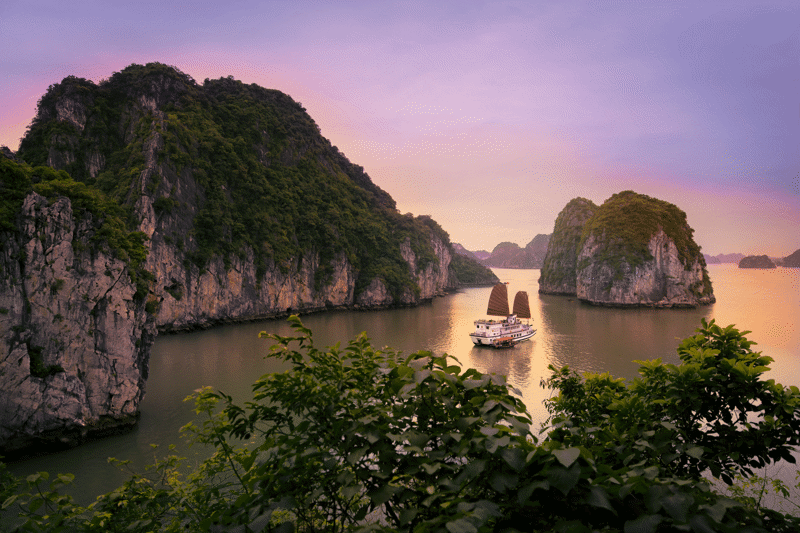 Boot die vaart in Bai Tu Long Bay tijdens de zonsondergang