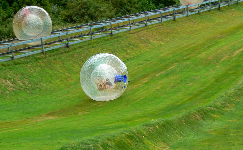 Mensen proberen Zorbing in Nieuw-Zeeland op een groene heuvel