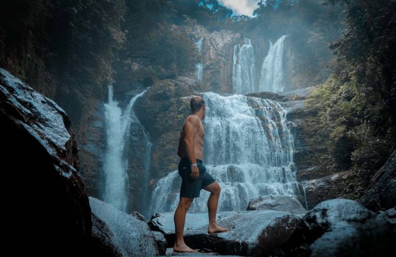 Man voor een grote waterval in Costa Rica
