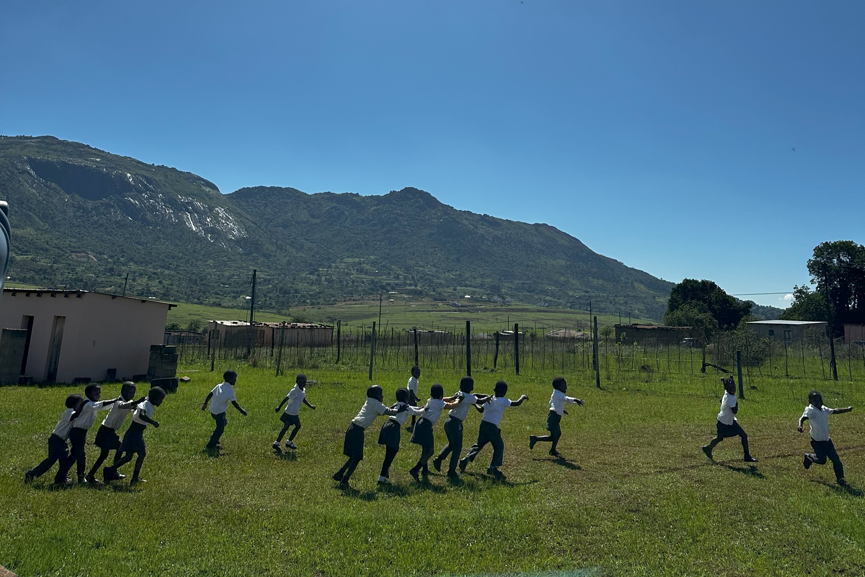 Man staat in een veld in Eswatini en kijkt naar het bergachtig uitzicht