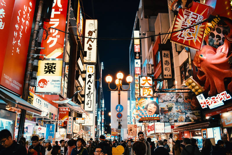 Drukke straat in Osaka met neonborden en veel voetgangers