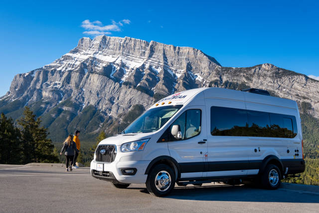 Deluxe Van Camper van Canadream staat op de weg voor bergen in Canada
