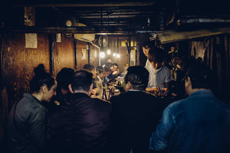 Groep mensen rond verschillende tafels in een Izakaya in Japan