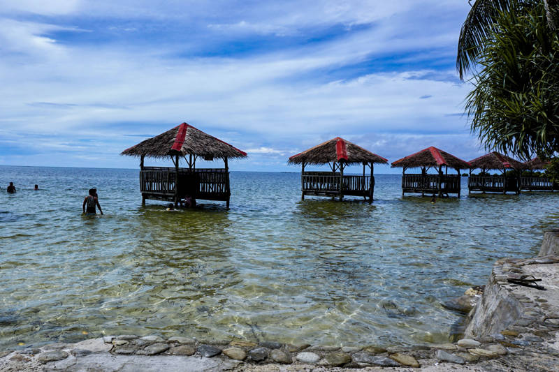 Mensen zwemmen bij hutten in het kristalheldere water van Palawan op de Filipijnen