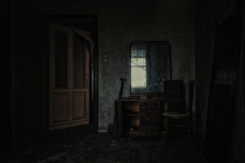 Creepy room in an old, haunted mansion with decaying walls and furniture being left behind by previous owners.